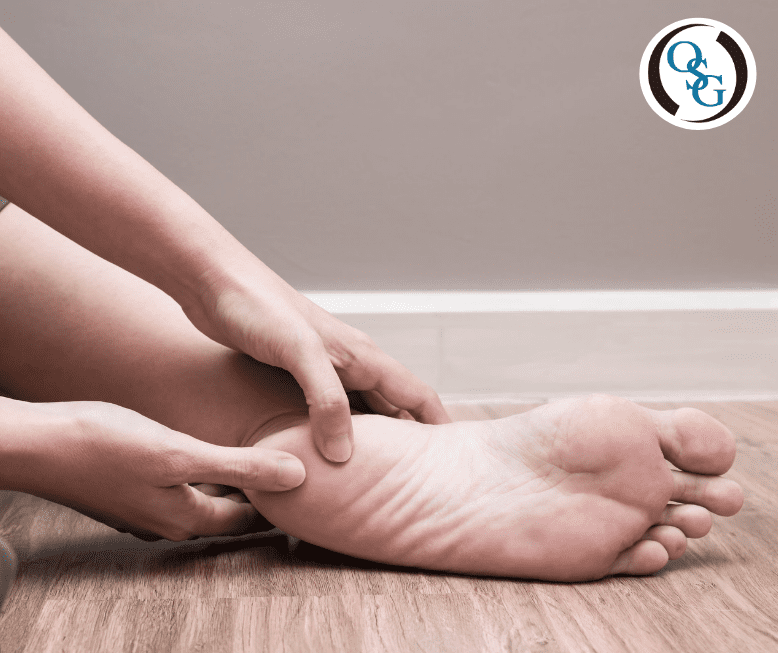 A person grabbing a their heel in pain while sitting on the floor