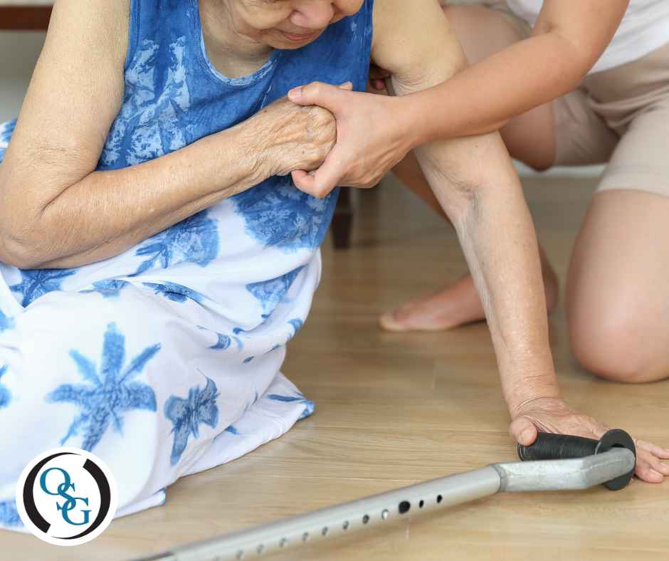 An elderly woman on the ground after a fall being helped up.
