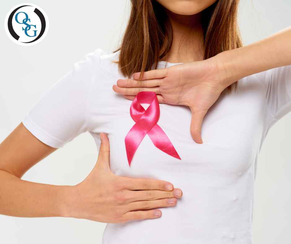 A woman in a white t shirt with a pink ribbon on her chest