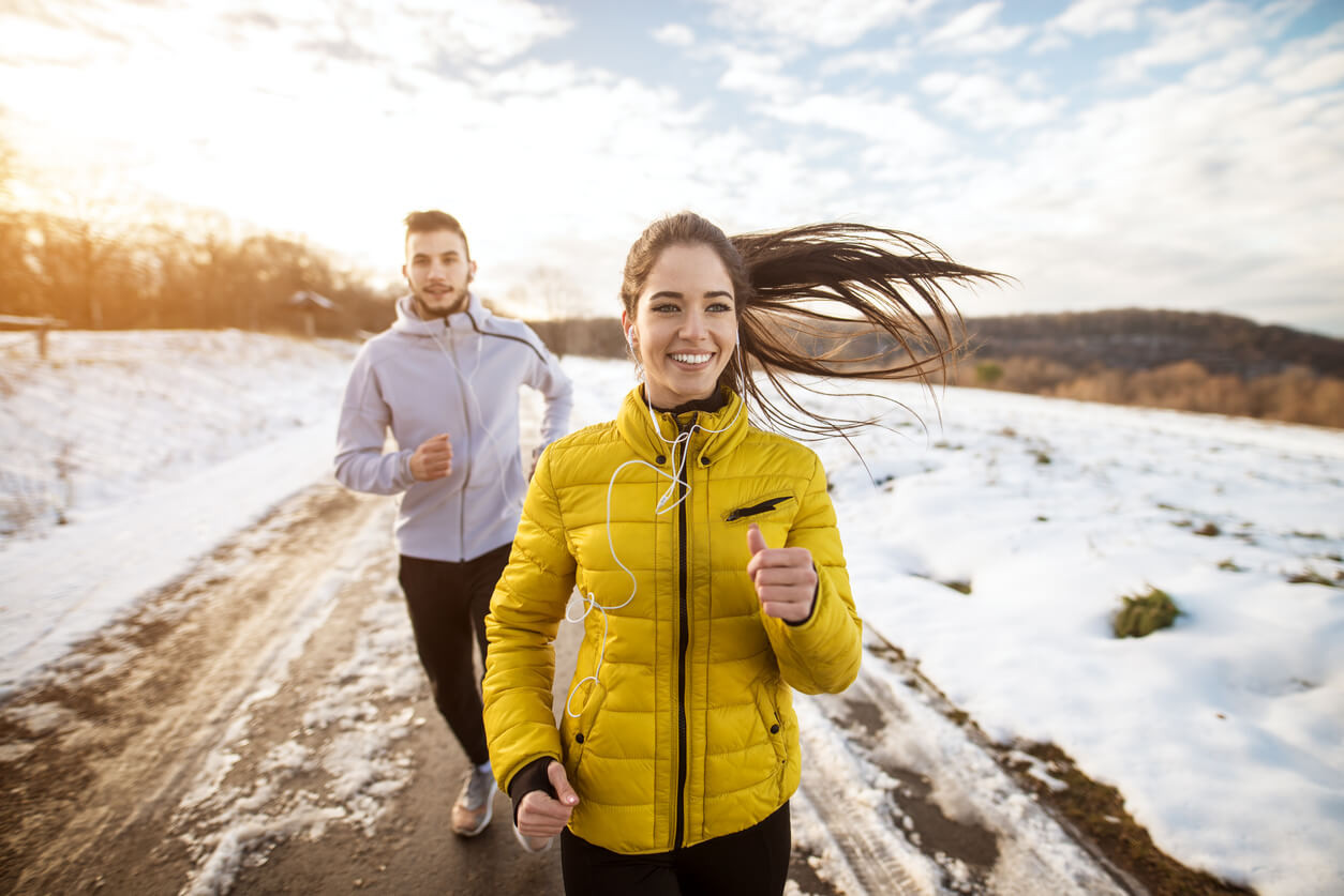 Active athletes sportive couple running with strong persistence on the road in winter nature in the morning.